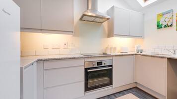 A modern kitchen with white cabinetry, a built-in oven, and a skylight.