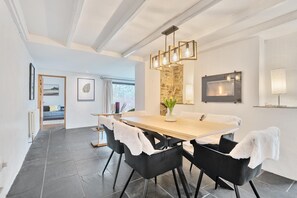 A modern dining area with a wooden table, black chairs, and a stone accent wall. - 4 Bed in Tresarrett (oc-b34254) (Blisland)