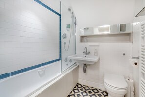 A bathroom with a white bathtub, a glass-enclosed shower, a sink, and a toilet.
