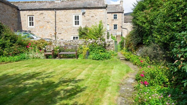 A stone building with a well-maintained garden, a bench, and a pathway leading to the entrance. - 2 Bed in Gunnerside (oc-ds1068) (Gunnerside)