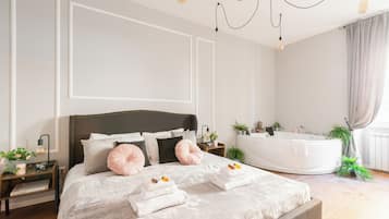 Ein modernes Schlafzimmer mit einem großen Bett, Nachttischen, einer integrierten Badewanne und einem Kronleuchter.