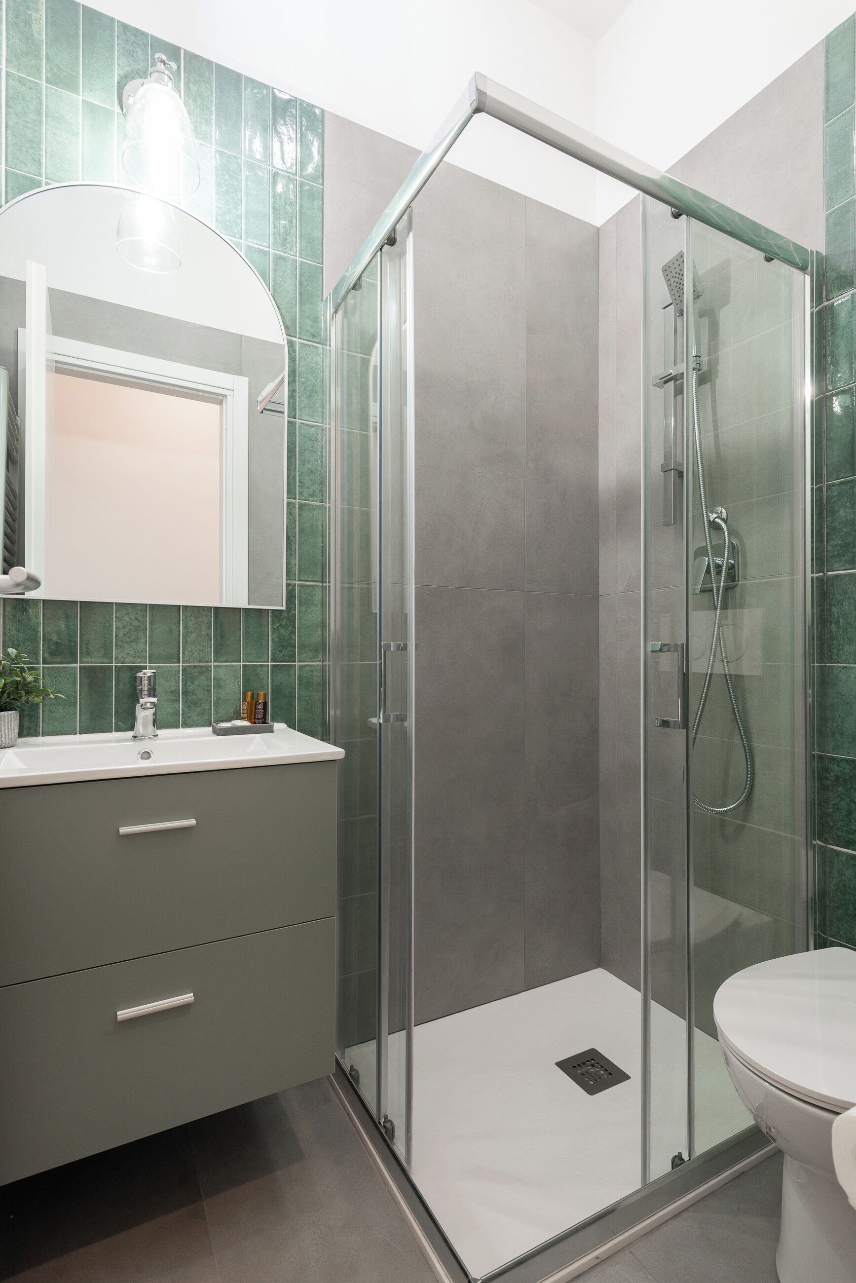 Un baño moderno con ducha de vidrio, lavamanos blanco y retrete.