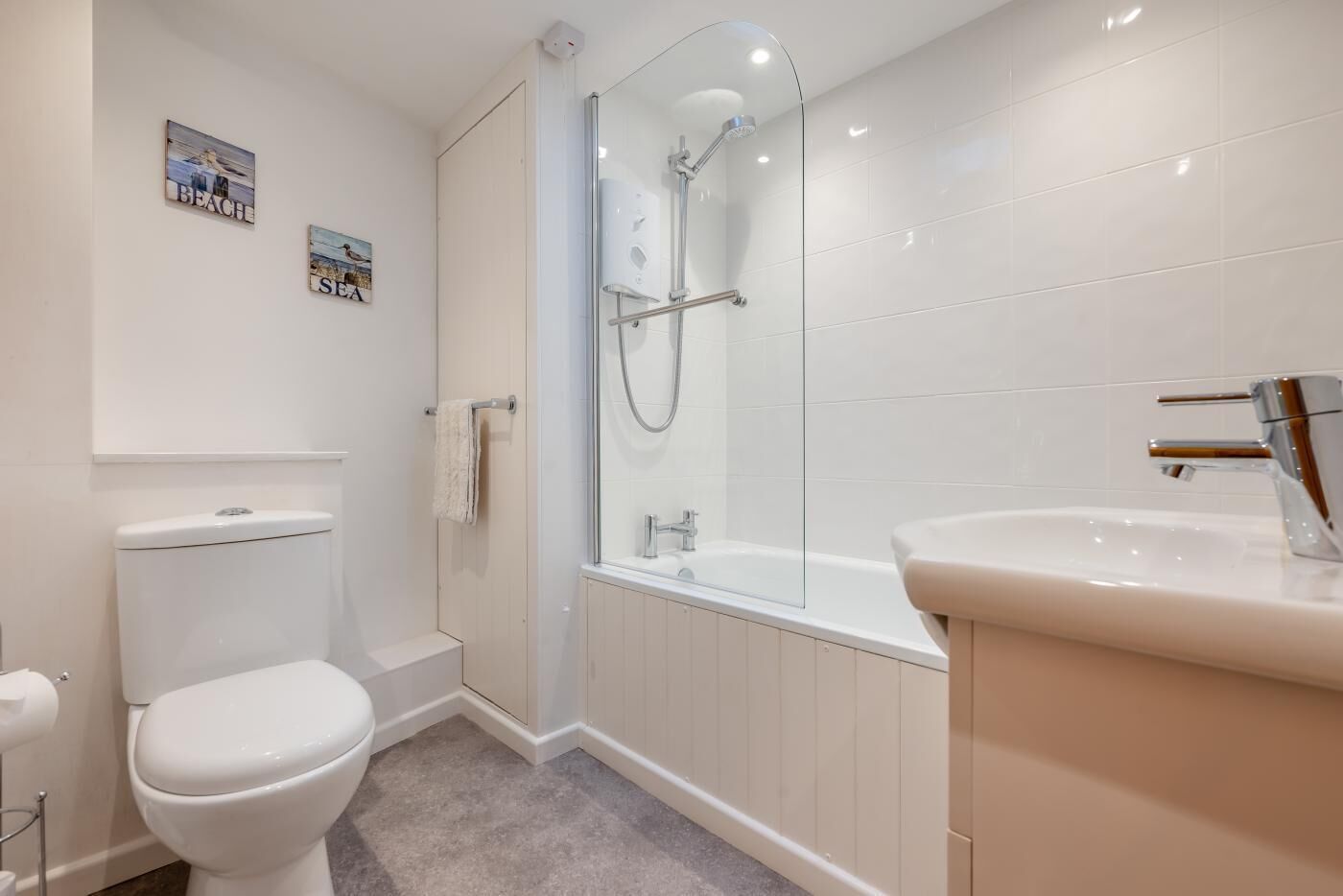 A modern bathroom with a toilet, a glass-enclosed shower, and a sink.