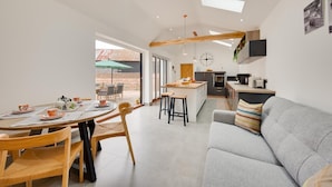 Een moderne keuken met een centraal eiland, een eethoek met een ronde tafel en een grijze bank.