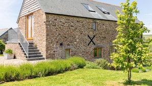 A stone building with a sloped roof, a staircase leading to the entrance, and a cross symbol on the wall. - 3 Bed in Loddiswell (oc-t34185) (Loddiswell)