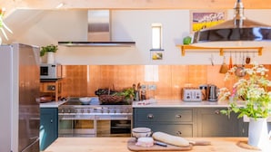 A modern kitchen with a central island, stainless steel appliances, and wooden cabinetry. - 3 Bed in Loddiswell (oc-t34185) (Loddiswell)