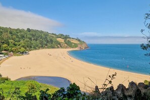 A beach with a clear view of the sea, a sandy shore, and a forested hillside. - 3 Bed in Loddiswell (oc-t34185) (Loddiswell)