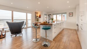 Een moderne keuken met een centraal kookeiland, barkrukken en uitzicht op de stad.