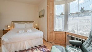 A bedroom with a bed, a window with a view, a radiator, and a chair. - 3 Bed in Brighton (oc-bt004) (Hove)