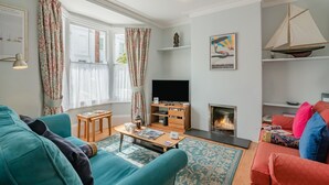 A living room with a fireplace, a television, and a bookshelf. - 3 Bed in Brighton (oc-bt004) (Hove)