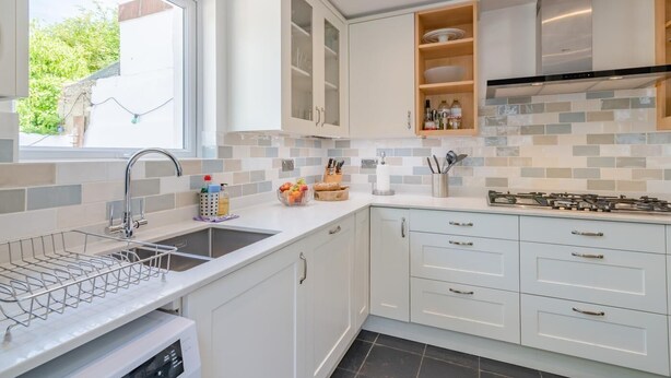 A modern kitchen with a built-in dishwasher, a window, and a tiled backsplash. - 3 Bed in Brighton (oc-bt004) (Hove)