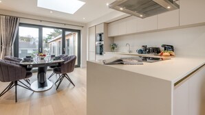 Una cocina moderna con una isla central, un comedor con mesa y sillas, y un ventanal que proporciona luz natural.
