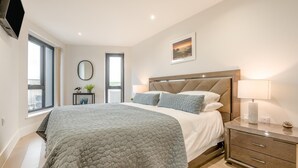 Un dormitorio moderno con una cama grande, mesitas de noche, un espejo y una ventana.