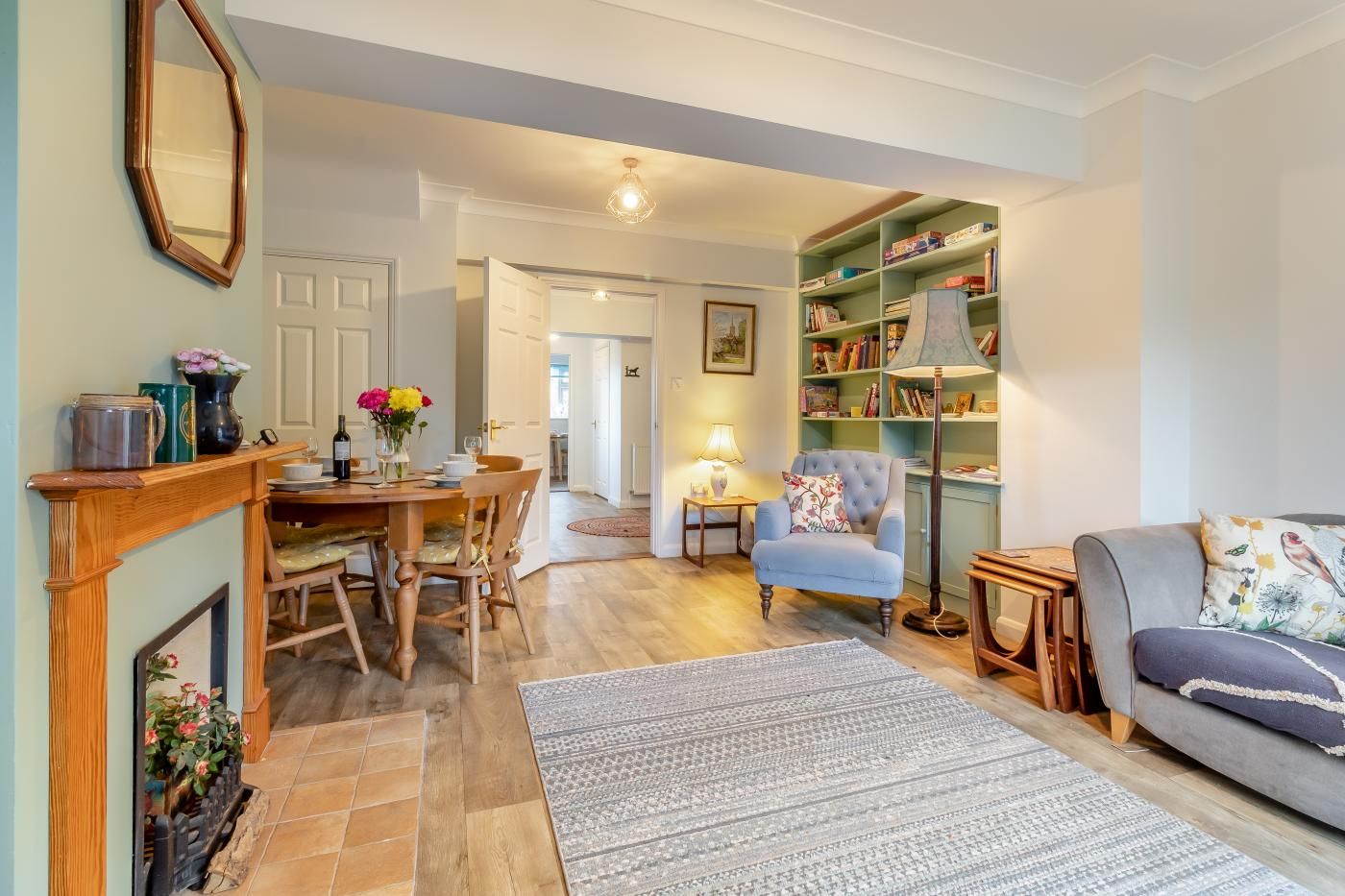 A cozy living room with a fireplace, a dining area, and a bookshelf.
