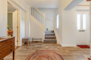 A staircase leading to a second floor, a wooden dresser, a small stool, and a colorful rug in a room with wooden flooring. - 3 Bed in Theberton (oc-1pcs) (Theberton)