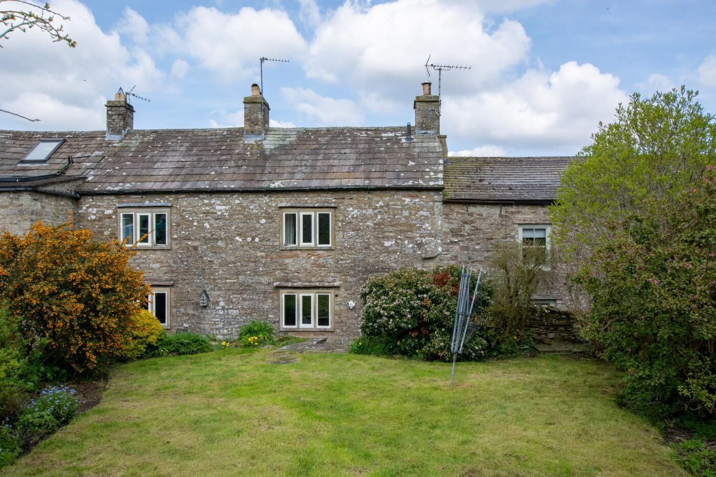 A stone house with a grassy yard and a metal sculpture.