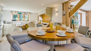 A modern kitchen with a central island, white cabinetry, and a dining area with a round table and chairs. - 2 Bed in Holmbury St. Mary (oc-midfb) (Holmbury Saint Mary)