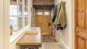A narrow hallway with a stone wall, wooden door, and a bench with a glass display case. - 3 Bed in Trellech (oc-j34206) (Trelleck)