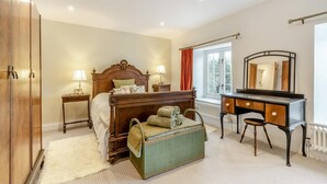 A bedroom with a wooden bed, bedside lamps, a dresser, a mirror, and a window with curtains. - 3 Bed in Trellech (oc-j34206) (Trelleck)