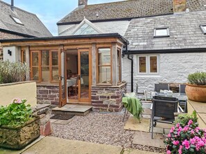 Ein gemütliches Cottage mit einer Holzveranda, einem Essbereich und einer Terrasse mit Tisch und Stühlen.