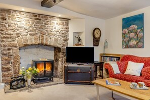 A living room with a stone fireplace, a flat-screen TV, a red sofa, and a painting on the wall.