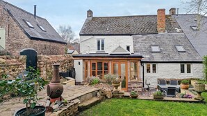 A stone house with a garden patio, a chimney, and a large pot. - 3 Bed in Trellech (oc-j34206) (Trelleck)