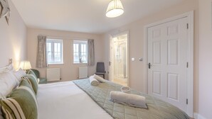 Ett hotellrum med en stor säng, två fönster med gardiner, en dusch och en dörr.