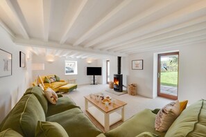 A modern living room with a green sofa set, a wooden coffee table, a flat-screen TV, and a wood-burning stove. - 4 Bed in Buxton (oc-dcoldd) (Hartington)