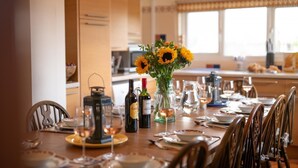 A dining table set with plates, cutlery, wine bottles, and a vase with sunflowers. - 6 Bed in Keswick (oc-ld177) (Keswick)