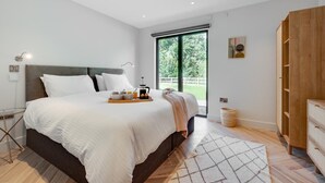 Een moderne slaapkamer met een groot bed, een ontbijtplateau, een koffiezetapparaat en uitzicht op de omgeving.