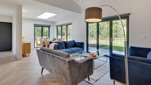 Een moderne woonkamer met een bank, salontafel en een eethoek met stoelen en een tafel.