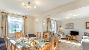 A modern living room with a dining area, wooden furniture, a flat-screen TV, and a large window with curtains. - 3 Bed in Lockton (oc-y119) (Lockton)