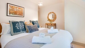 Ein ordentlich eingerichtetes Hotelzimmer mit einem großen Bett, einem Nachttisch, einem Spiegel und einem gerahmten Kunstwerk an der Wand.