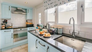 Una cucina moderna con mobili azzurri, un lavello in acciaio inossidabile e una finestra vista cielo.