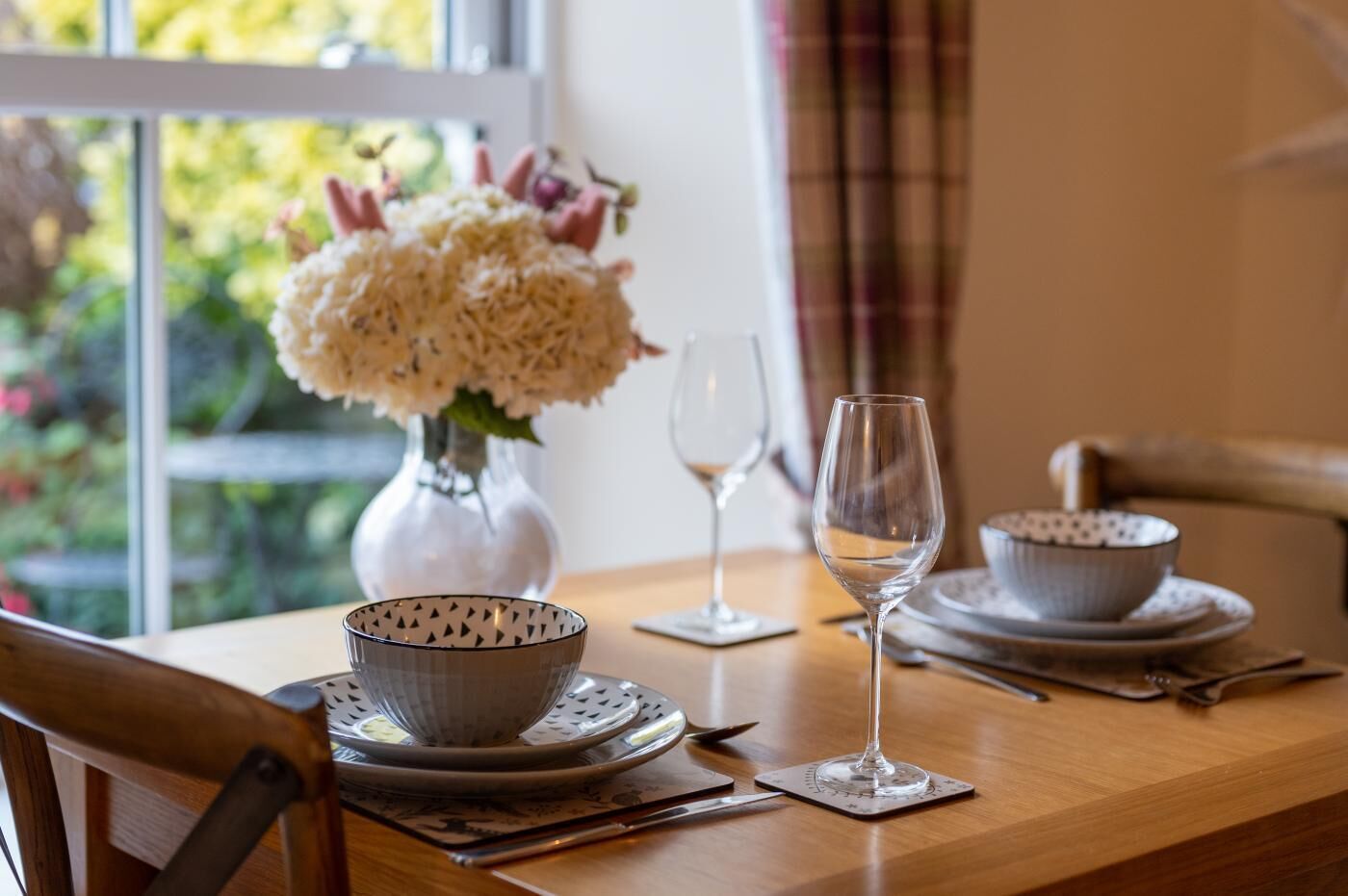A dining table set with a bowl, a wine glass, and a vase with flowers.