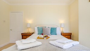 Une chambre d’hôtel avec un lit, deux tables de chevet, une porte et une petite table de nuit avec une lampe.
