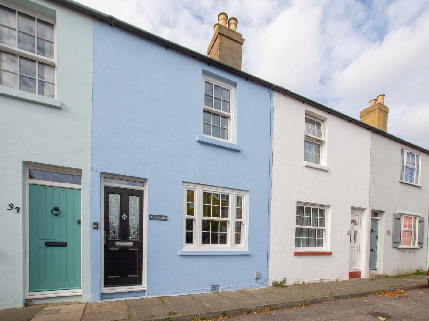 A row of terraced houses with distinct pastel colors, numbered doors, and traditional window designs.