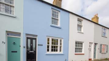 A row of terraced houses with distinct pastel colors, numbered doors, and traditional window designs.