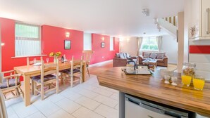 A modern kitchen with a wooden countertop, a dining area with a table and chairs, a living room with sofas, and a staircase leading to an upper level. - 2 Bed in Sledmere (oc-ey103) (Sledmere)