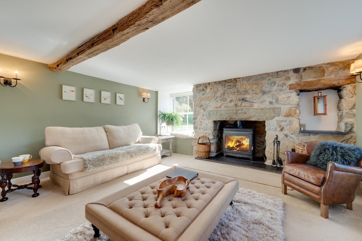A cozy living room with a stone fireplace, a sofa, a coffee table, and a leather armchair.