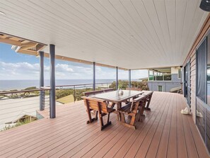A wooden deck with a table and benches, overlooking a coastal landscape.
