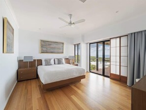 A bedroom with a bed, nightstands, a ceiling fan, a painting, and a view through a sliding glass door. - Ocean Views—Refined Hilltop Residence by the Sea (Yallingup)