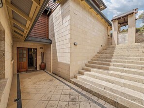 Ein Gebäude mit steinverkleideter Fassade, einer Holztür und einer Treppe, die zu einem überdachten Bereich führt.