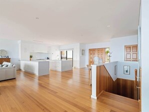 A spacious living area with a kitchen island, wooden flooring, and a built-in seating area.