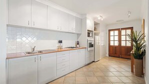 Uma cozinha moderna com armários brancos, bancada de madeira e chão de azulejo.
