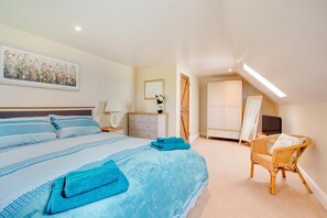 Une chambre à coucher avec un grand lit, une commode, une chaise, un miroir et un tableau accroché au mur.