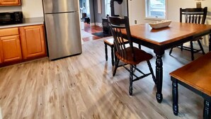Een moderne keuken met houten kastjes, een roestvrijstalen koelkast en een eethoek met een houten tafel en stoelen.