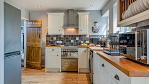 Une cuisine moderne avec des meubles blancs, un plancher en bois et un four encastré.