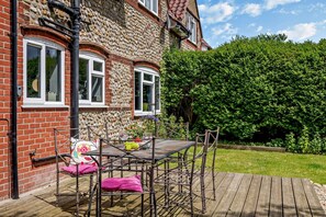 A house with a stone facade, a wooden deck, and a garden.