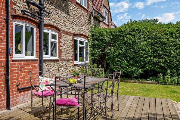 A house with a stone facade, a wooden deck, and a garden.